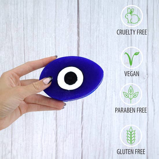 Hand holding blue evil eye glycerin soap with eye symbol, cruelty-free, vegan, paraben-free, gluten-free personal care product for protection