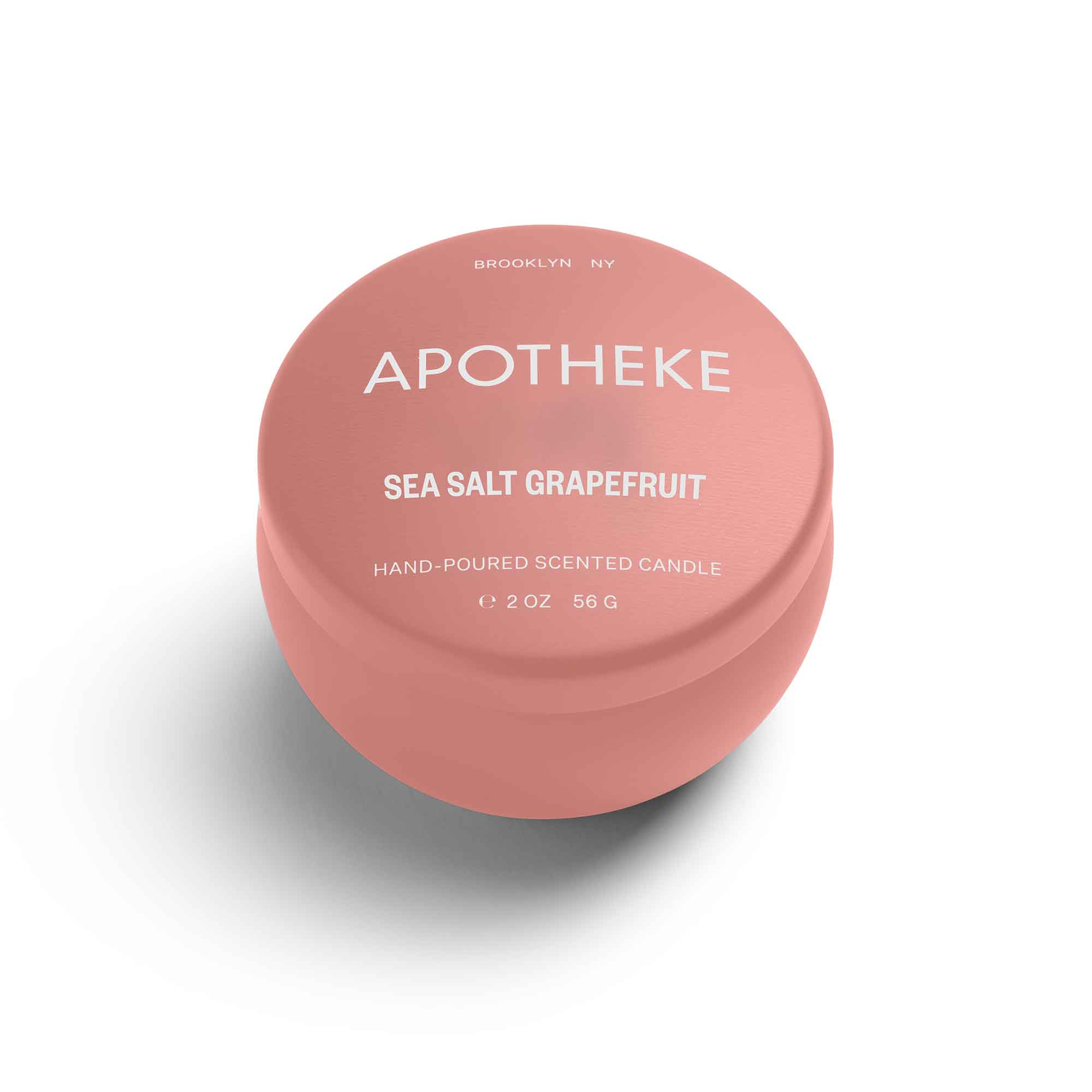 Round pink candle container with white text reading 'Sea Salt Grapefruit' and 'Hand-Poured Scented Candle' in a minimalistic design