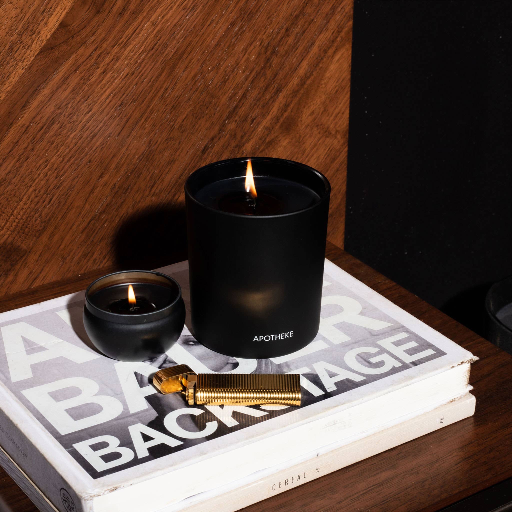Close-up of a black charcoal mini candle on a wooden surface with a textured background, highlighting the candle's sleek design