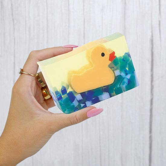 Hand holding a yellow rubber duck-shaped fruity soap with colorful beads, showcasing its playful design for self-care