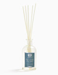 Glass bottle of Antica Farmacista Santorini reed diffuser with beige reeds, label displaying elegant blue design, home fragrance decor