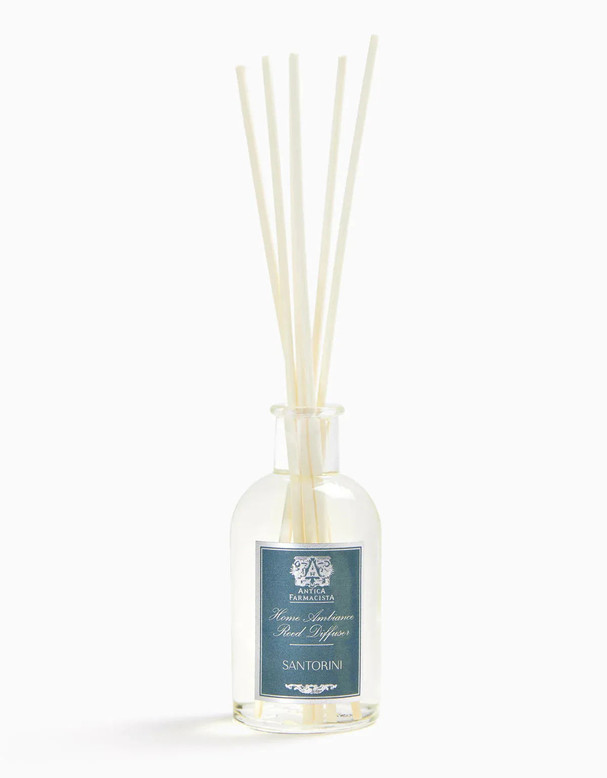 Glass bottle of Antica Farmacista Santorini reed diffuser with beige reeds, label displaying elegant blue design, home fragrance decor