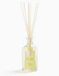 Glass bottle of Lemon Verbena Diffuser with white reed sticks, clear liquid inside, label with yellow accents, elegant home fragrance decor
