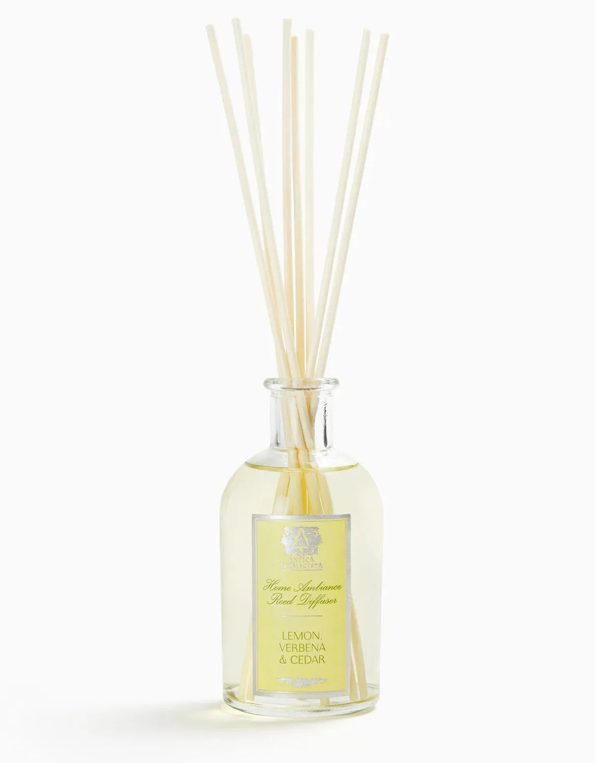 Glass bottle of Lemon Verbena Diffuser with white reed sticks, clear liquid inside, label with yellow accents, elegant home fragrance decor