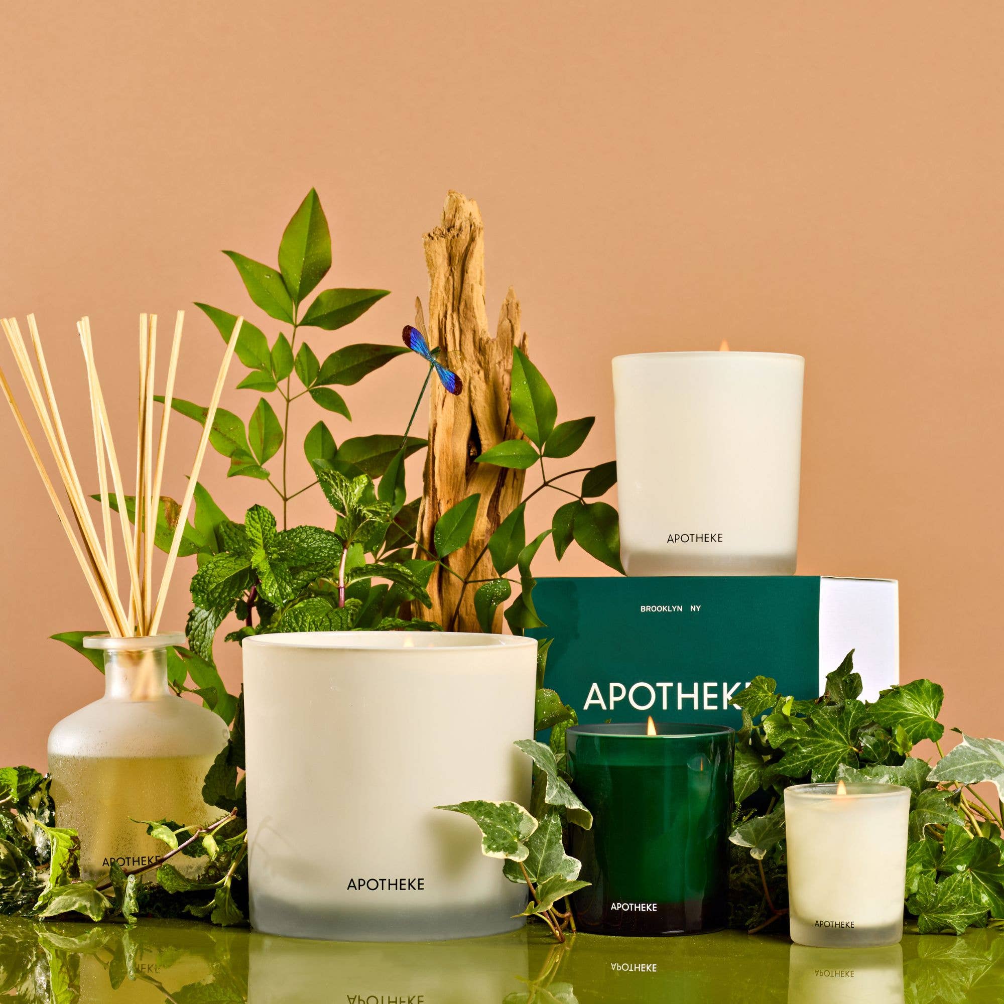 Close-up of a white ceramic candle holder with a lit candle, surrounded by green leaves and decorative elements, cozy ambiance