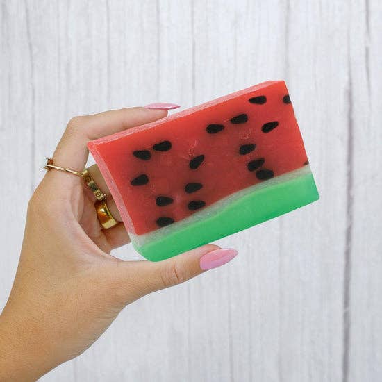 Hand holding watermelon glycerin soap with red and green layers, showcasing its playful, fruit-inspired design