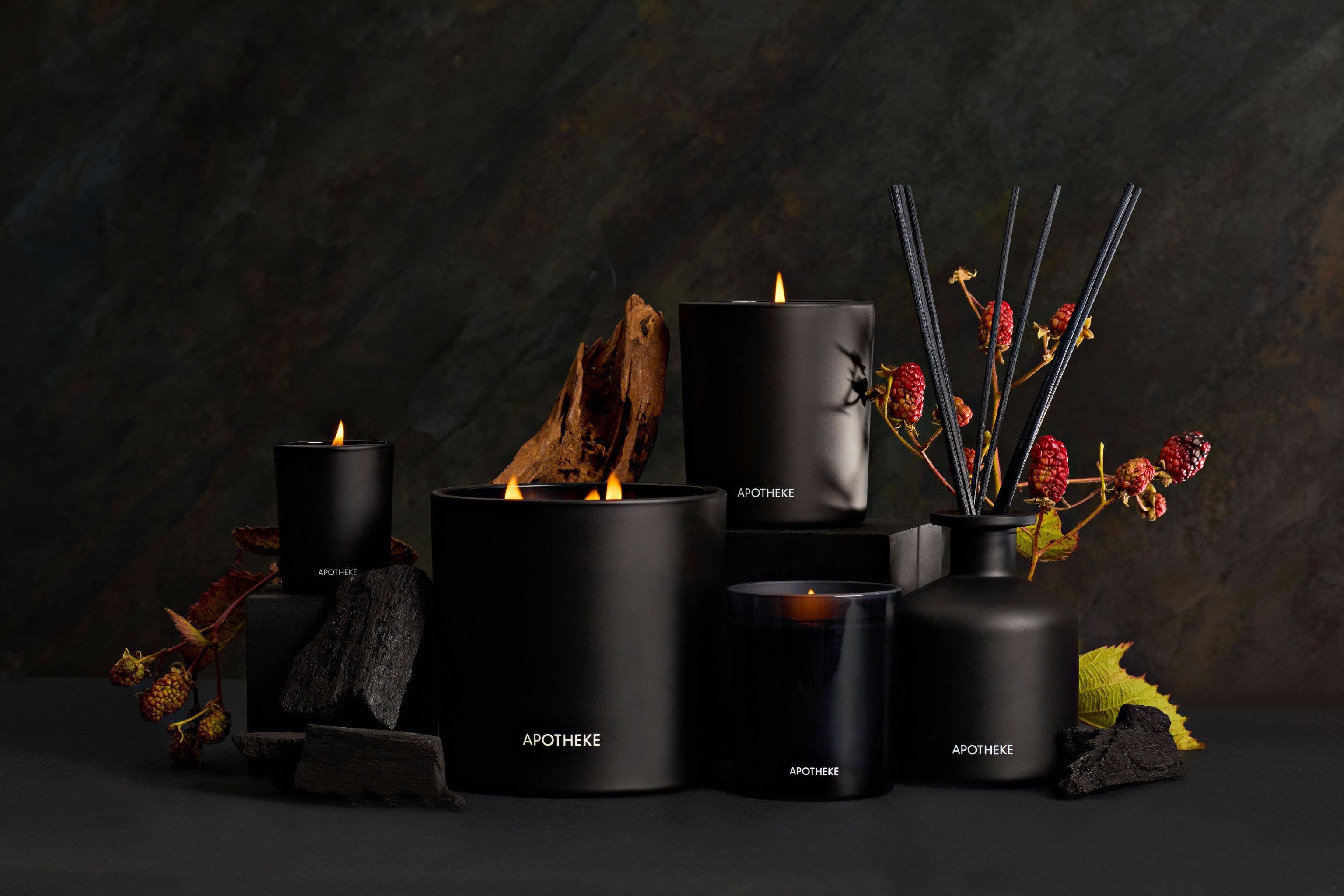 Elegant black scented candle with a flame, surrounded by natural elements like wood and berries, creating a cozy ambiance
